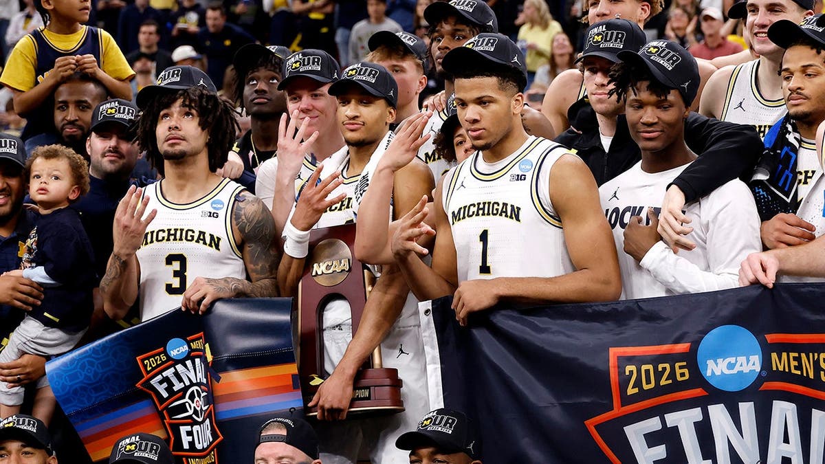 Nimari Burnett holding Midwest Regional Championship trophy with Michigan Wolverines teammates