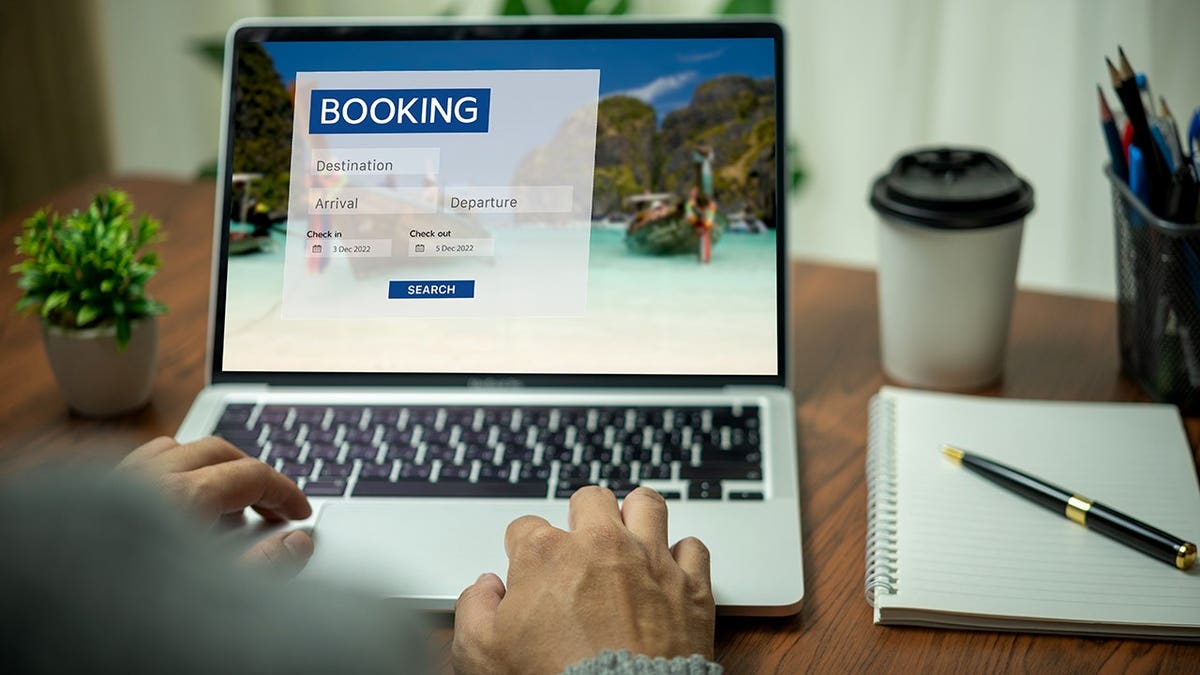 A man using a laptop to search for accommodation and airlines on an online booking platform.