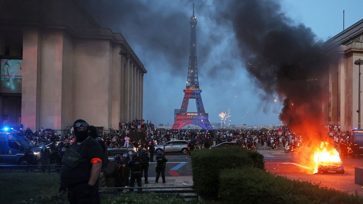 A car burns and fireworks explode as police watch PSG supporters celebrate in Paris, Saturday, May 30, 2026.