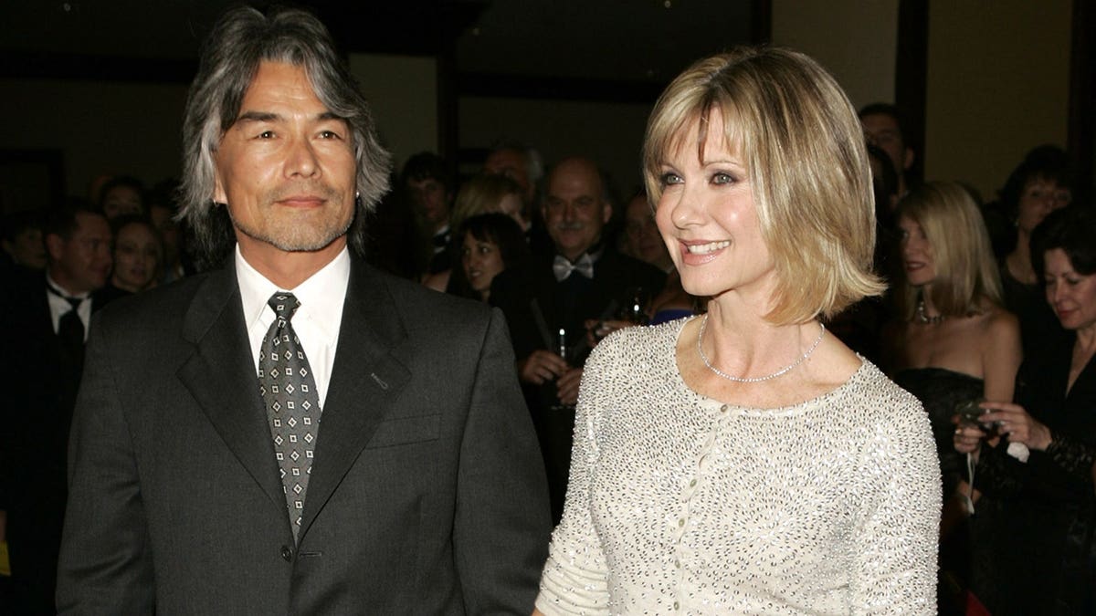 Patrick McDermott and Olivia Newton-John posing on red carpet at Century Plaza Hotel