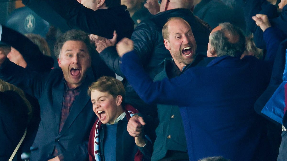 Prince George of Wales and Prince William, Prince of Wales, standing at a football stadium