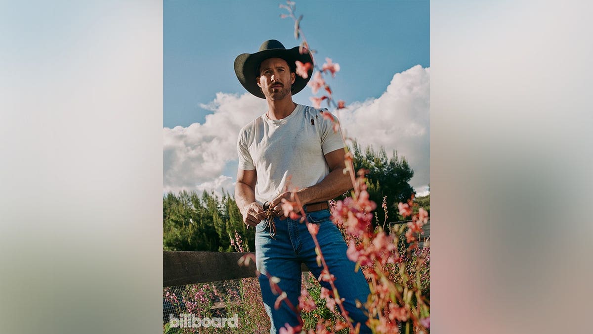 Riley Green in a field of flowers in photos for Billboard in May 2026.
