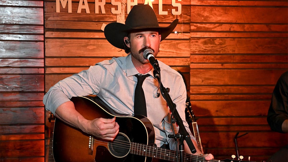 Riley Green singing and playing his guitar.
