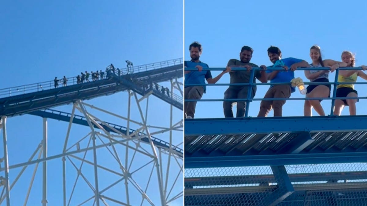 People walk down the track to evacuate a large blue roller coaster at Six Flags.