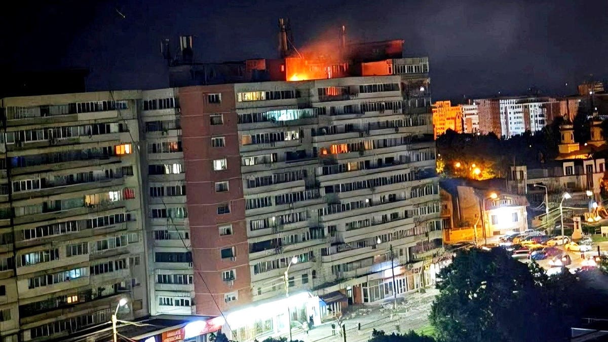 A fire burns on the roof of a 10-story block of flats in Romania after a drone crashed into the building