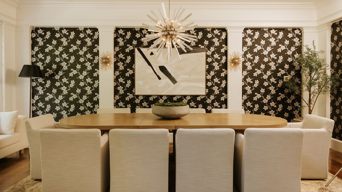 A dining room with black and white wallpaper and a unique light fixture.
