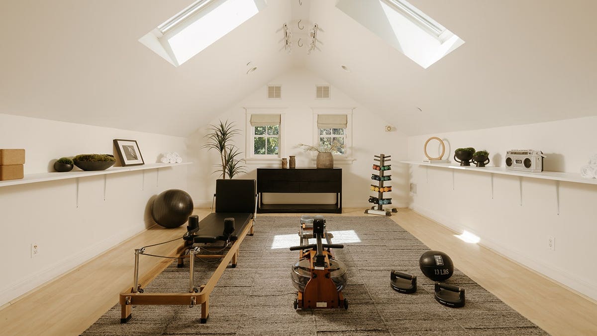 A room with a pointed ceiling and workout equipment.