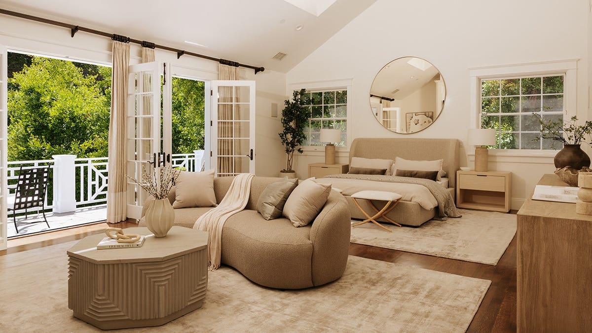 A spacious bedroom with a vaulted ceiling, hardwood flooring and a balcony outside.