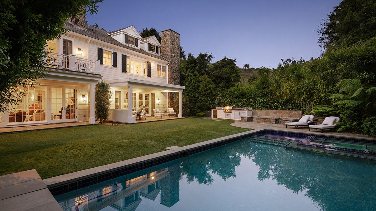A backyard with a large swimming pool and grass area.