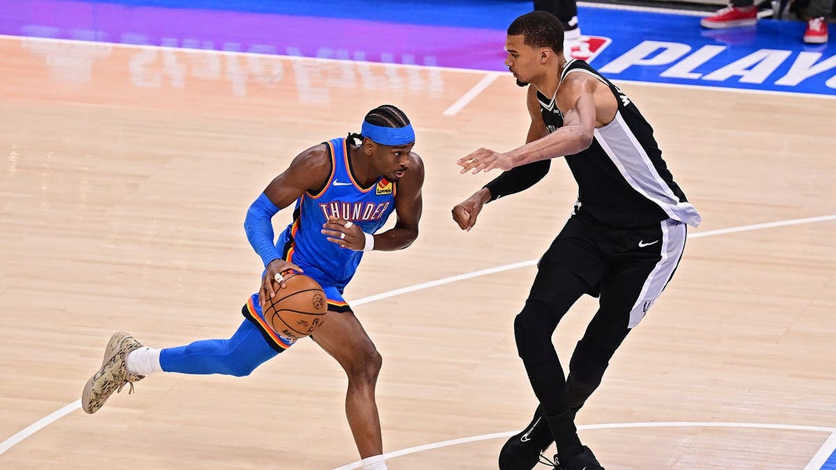Shai Gilgeous-Alexander drives to the handbasket  against Victor Wembanyama during NBA game.