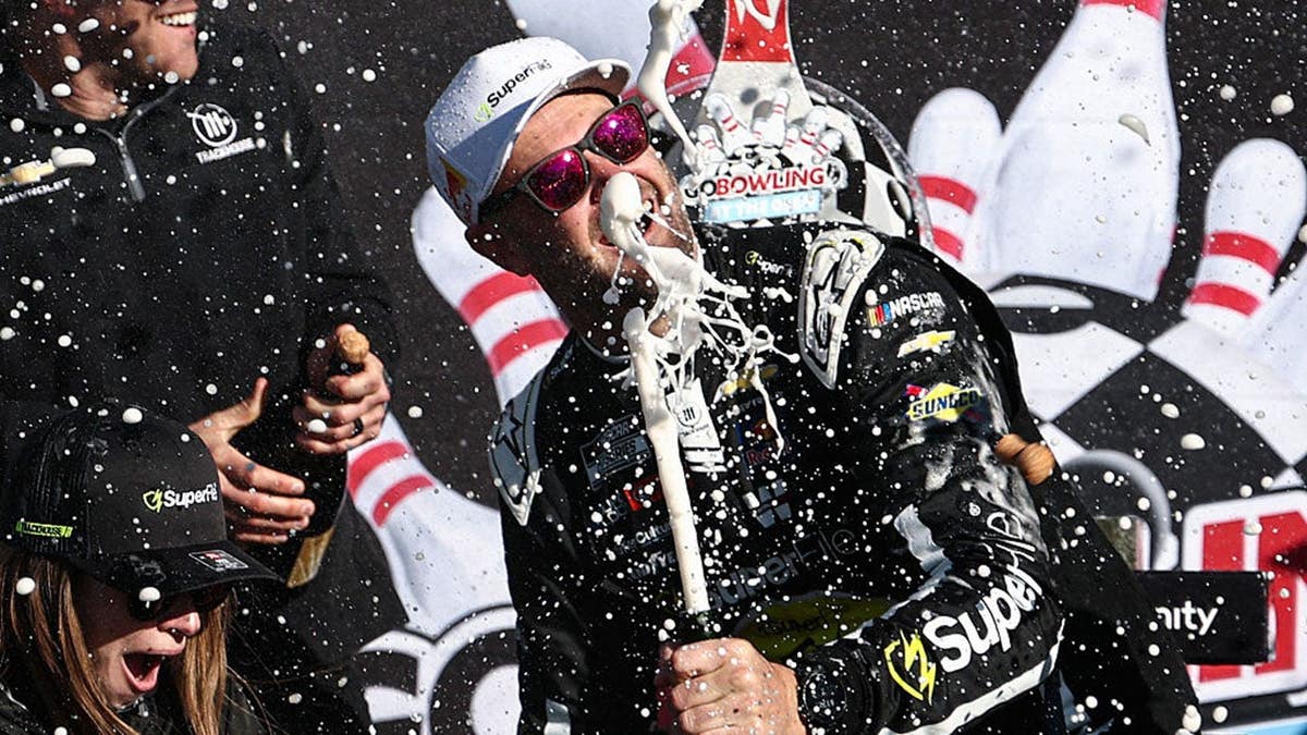 Shane Van Gisbergen spraying champagne in victory lane at Watkins Glen International
