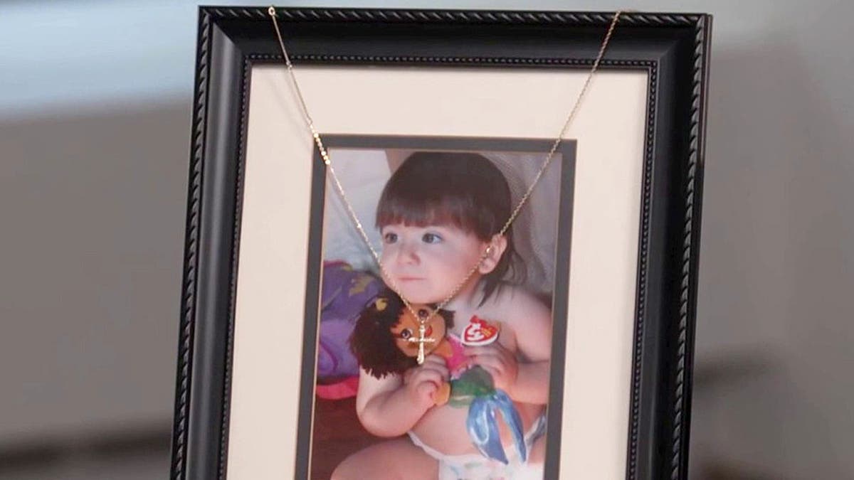 Baby photo of Sheridan Gorman with cross placed around frame.