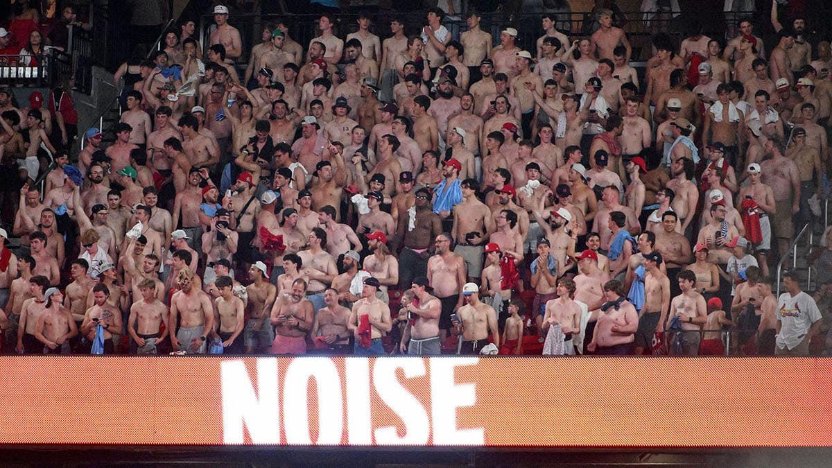 A group of shirtless fans cheering in seats at Busch Stadium