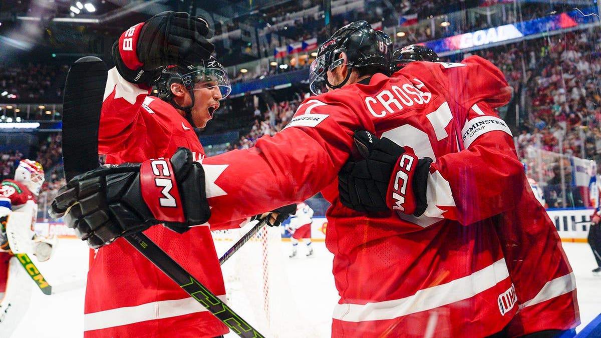 Sidney Crosby and Dylan Cozens celebrating Macklin Celebrini's goal on ice hockey rink