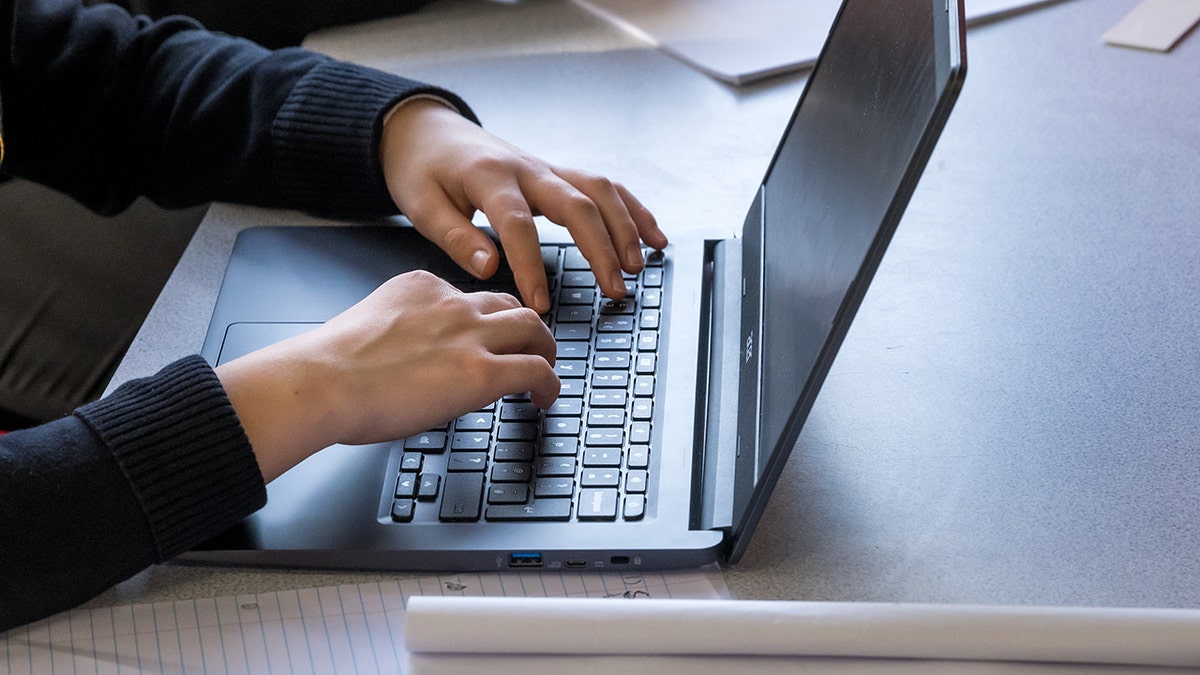 Student typing on their laptop.