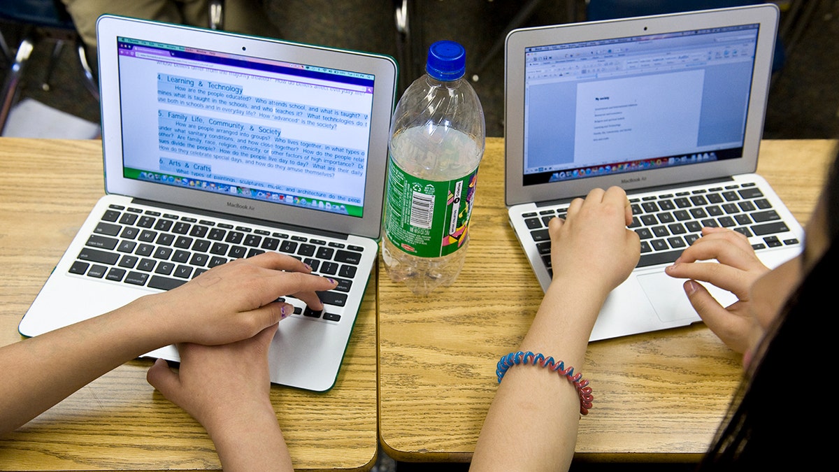 Students typing on their laptops at school.