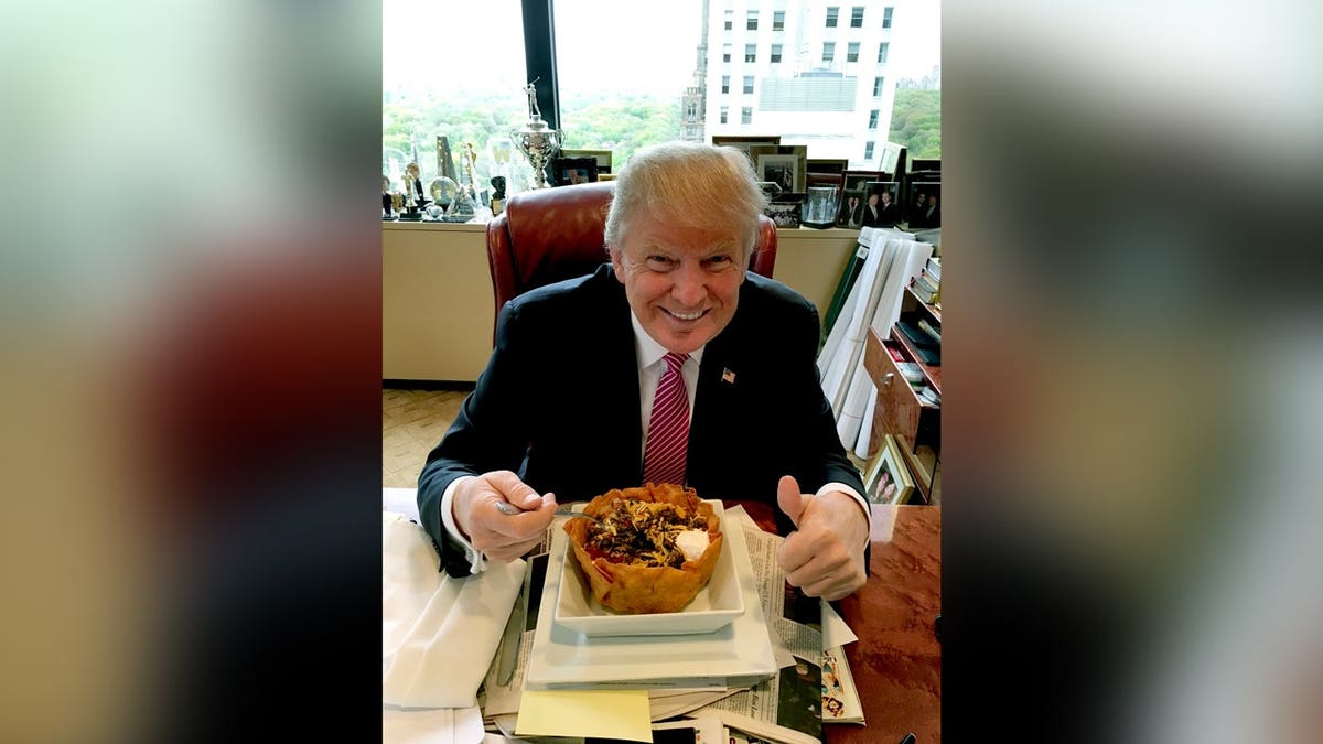 Trump smiling with a taco bowl giving a thumbs up.
