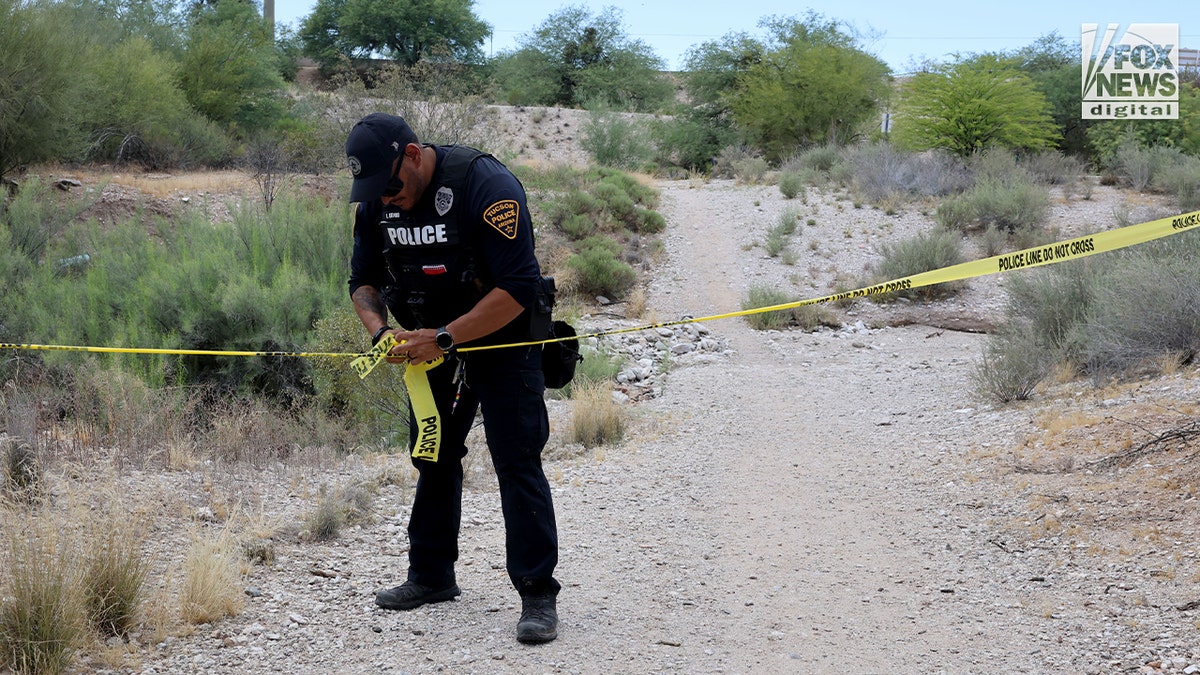 A Tucson police officer puts up police tape near where human remains were found in an ephemeral river while searching for Nancy Guthrie, the 84-year-old mother of "Today" co-host Savannah Guthrie. 
