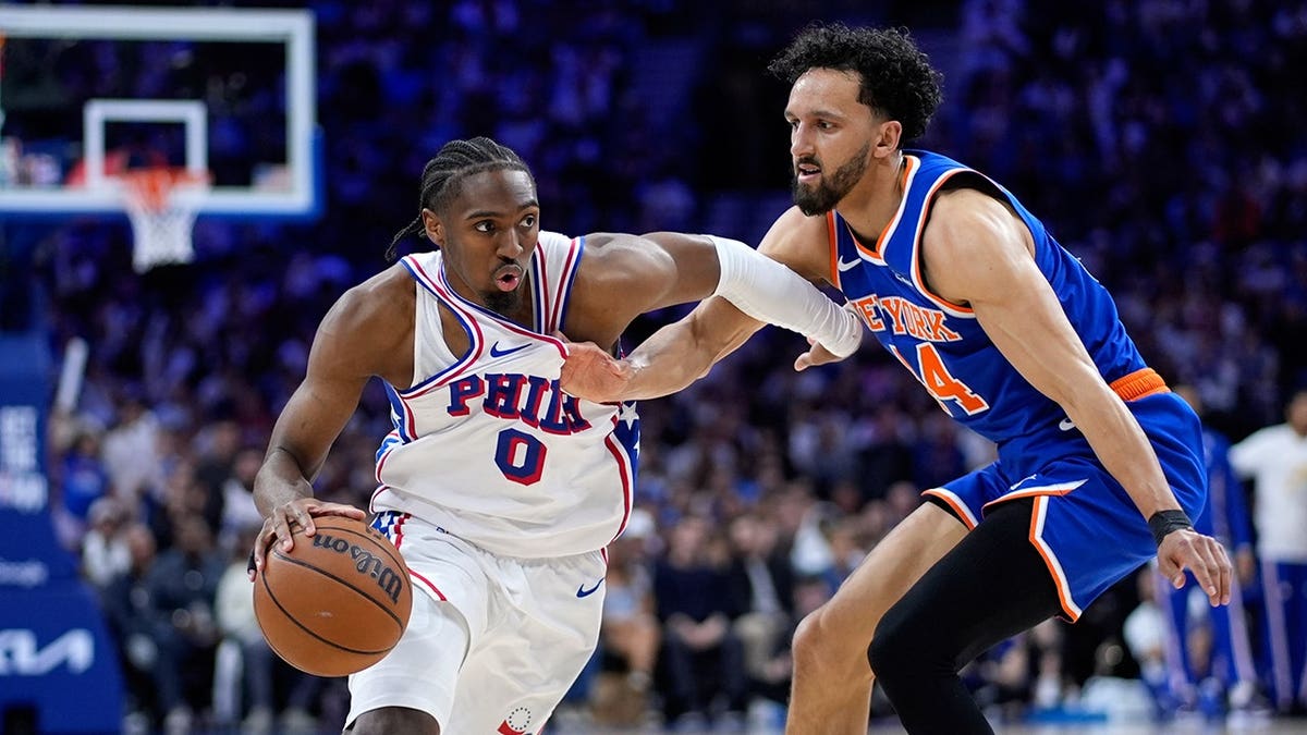 Tyrese Maxey dribbling basketball past Landry Shamet during NBA playoff game in Philadelphia