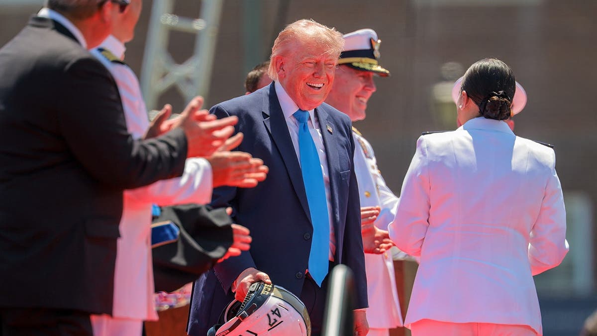 Cadet Savannah Riera presenting a football helmet to President Donald Trump at Coast Guard Academy ceremony