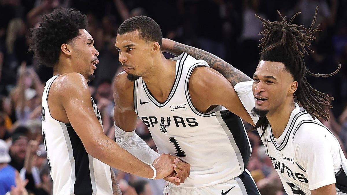 Víctor Wembanyama anota una canasta mientras Dylan Harper y Stephon Castle le felicitan