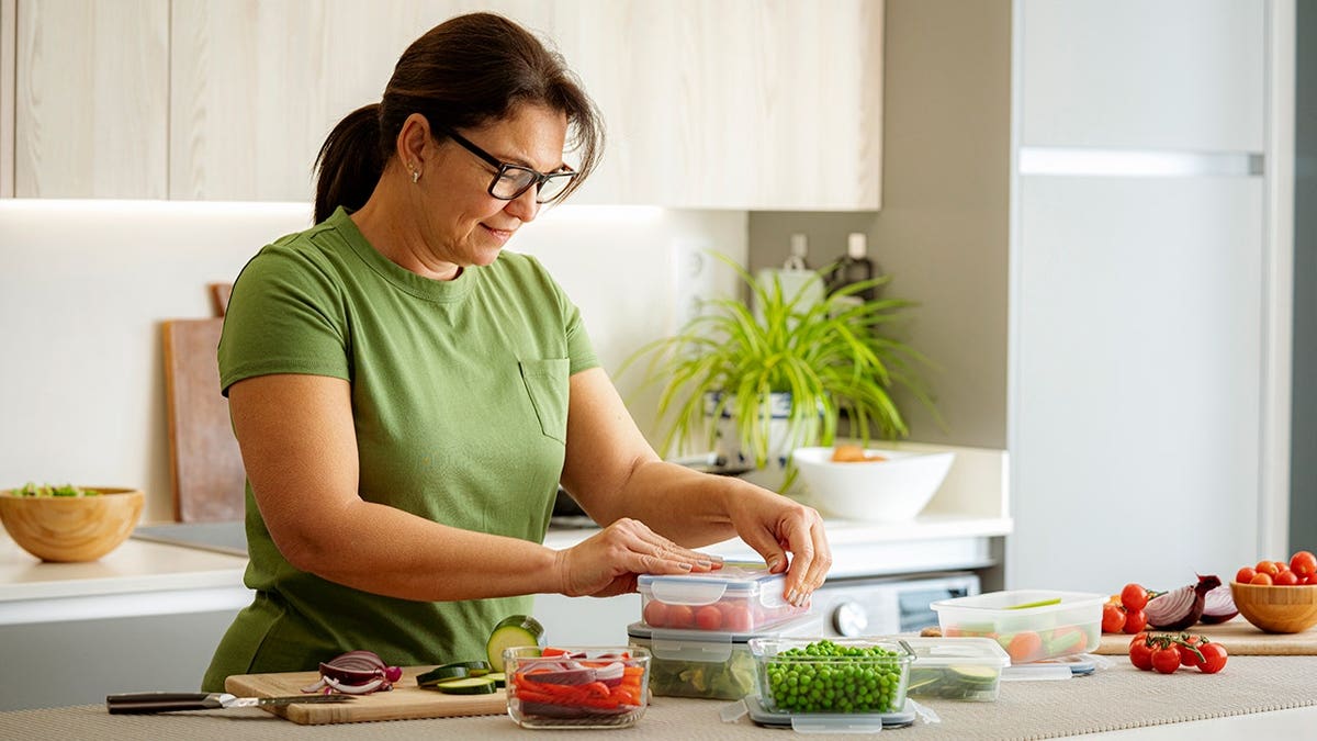 Woman preparing vegetables in plastic airtight food containers in a kitchen