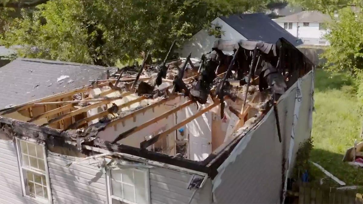 A fire-damaged house sits with a collapsed roof seen from above.