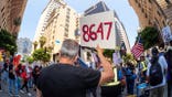 Person holds sign with '86 47' message on it