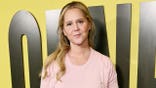 Amy Schumer walks red carpet wearing pink shirt