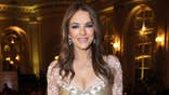 Elizabeth Hurley standing in a black dress at a gala event