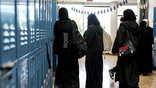 Female students in hijabs at school lockers