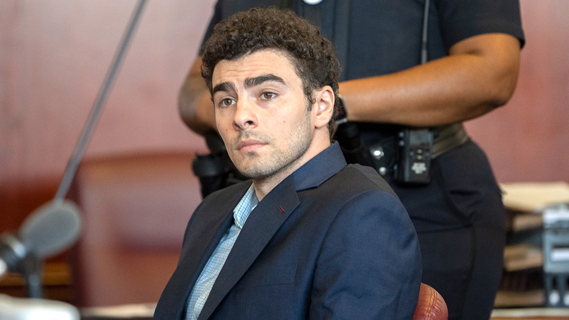 Luigi Mangione appearing at an evidence suppression hearing in a courtroom.