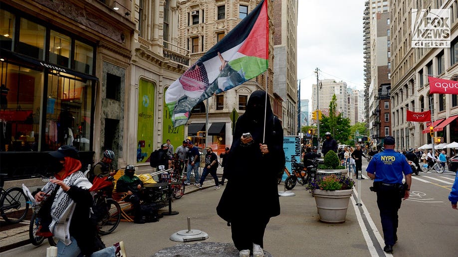 Woman-carrying-Abu-Obaida-imagery-during-Manhattan-protest.jpg