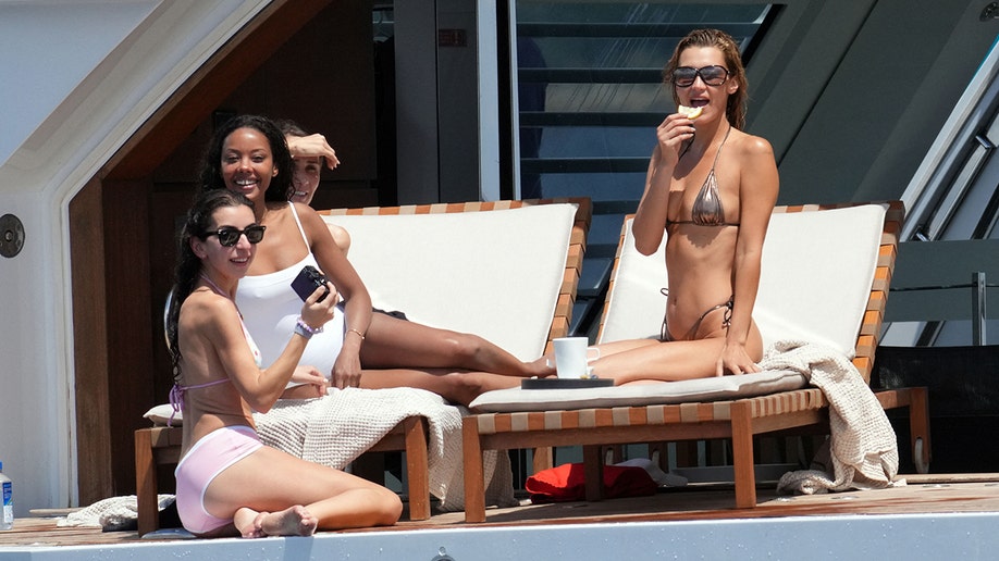 Bella Hadid eating a potato chip while on a yacht with her friends.