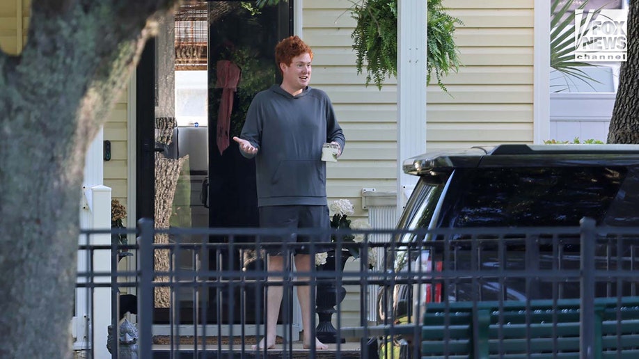 Buster Murdaugh sits on the front porch of a home while holding a coffee cup.