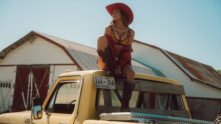 Jana Kramer on top of a pickup truck in a leopard-print bra.