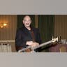 Dave Mason performs on stage with a guitar.
