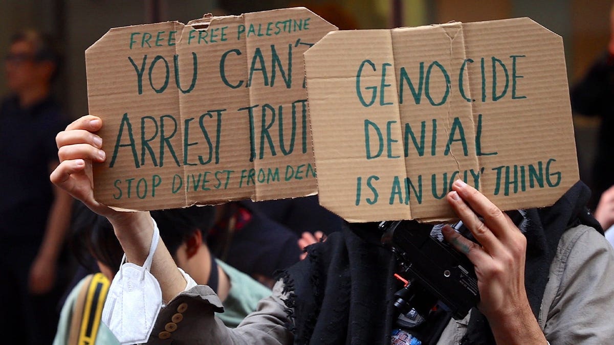 A person holds anti-Israel cardboard signs