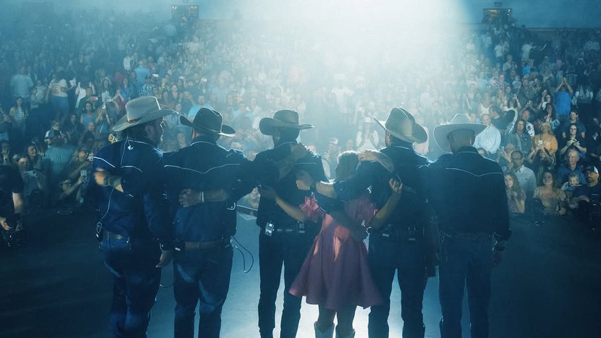 Anne Wilson no palco de costas com sua banda country.