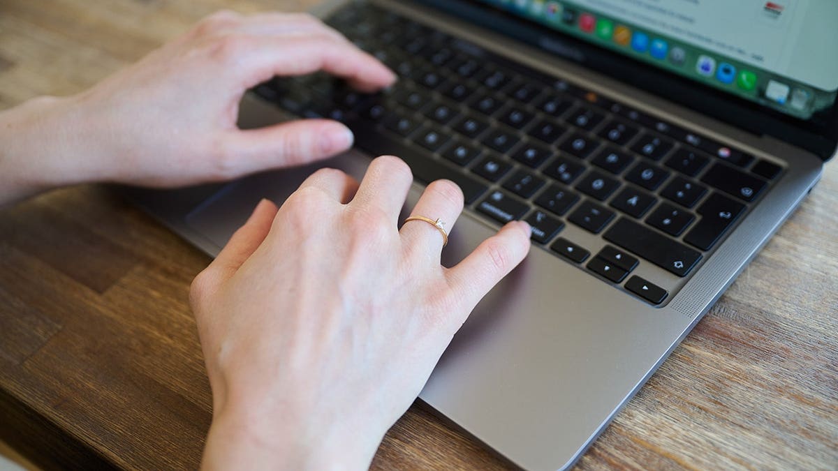 Woman typing on a MacBook.