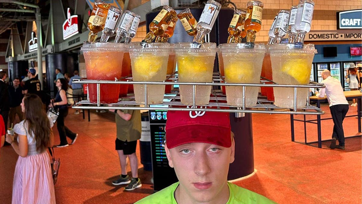A concession worker has mixed drinks on his head