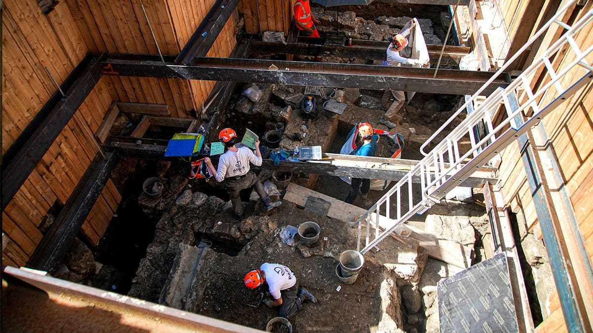 View of archaeologists excavating pit