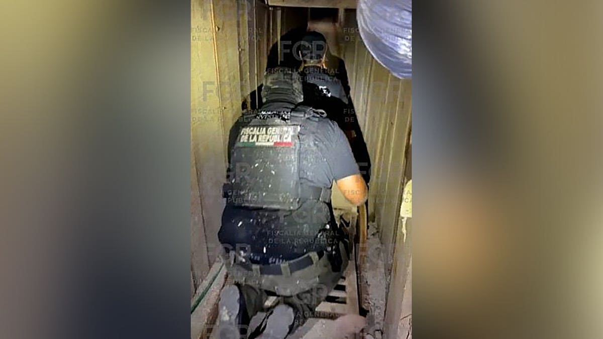 Agentes federales mexicanos se arrastran por un estrecho túnel subterráneo durante una operación policial.