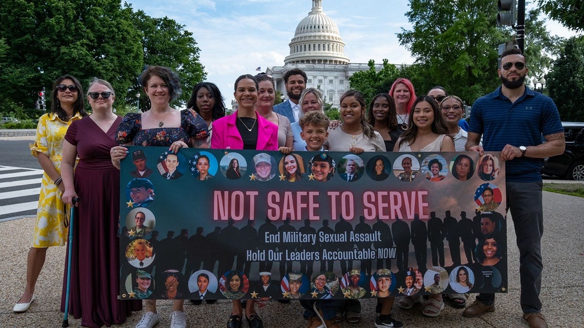 A group of military families and advocates stand near the U.S. Capitol holding a banner that reads