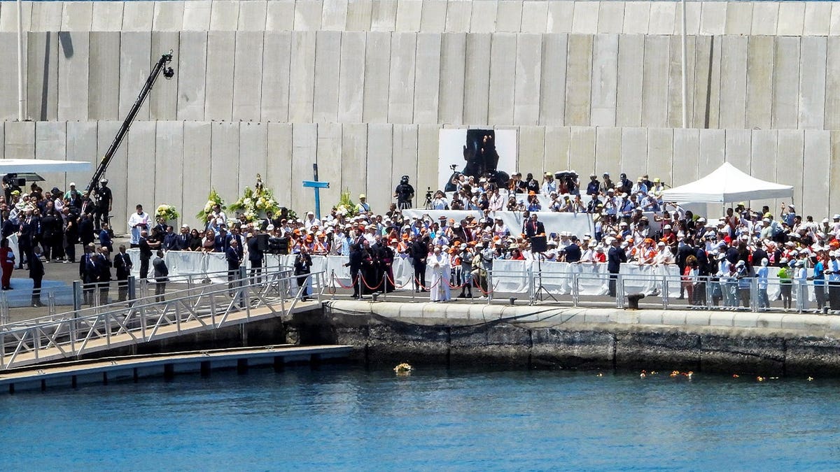 Pope Leo XIV observes a minute of silence after making a floral offering to migrants lost at sea at the dock of the Port of Arguineguin in Gran Canaria, Spain