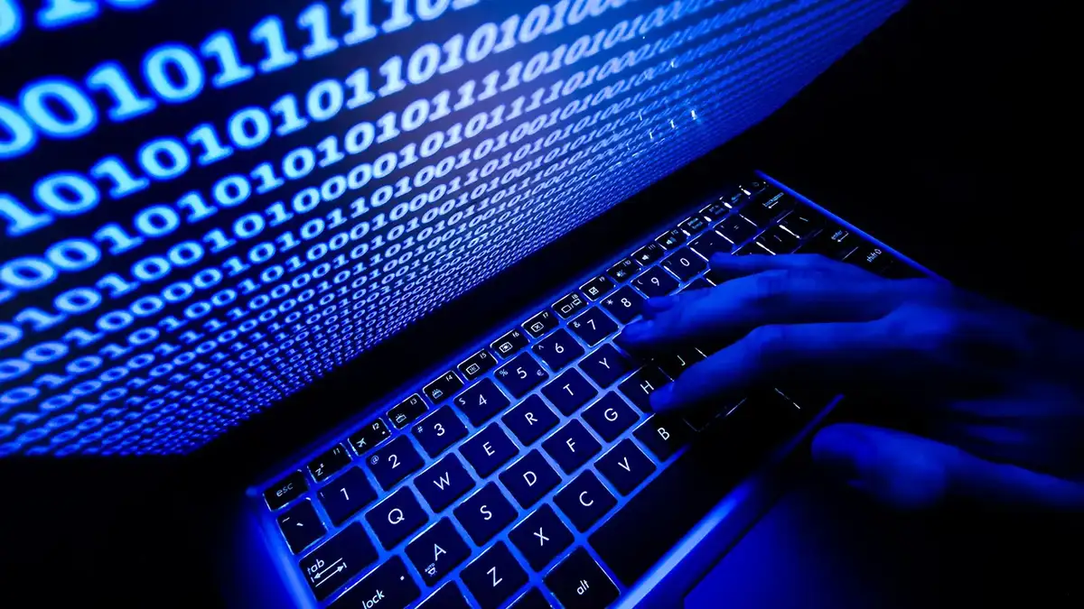 Scammer typing on their laptop.