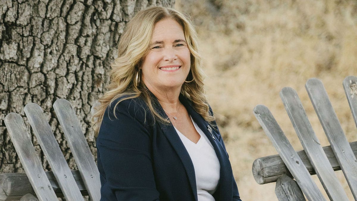Sidney Greenbush wearing a dark blazer and a white shirt sitting outdoors.