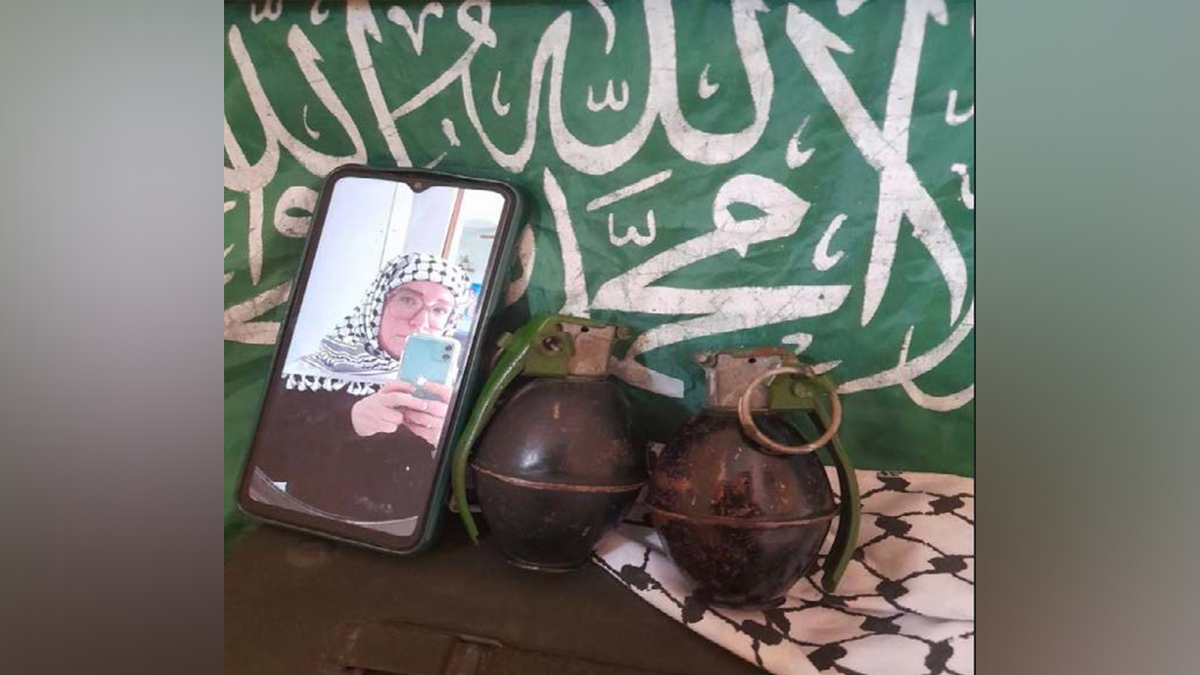 Catherine Beth Washburn pictured with two hand grenades in front of Hamas flag.