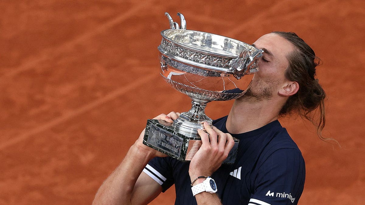 Alexander Zverev kissing La Coupe des Mousquetaires trophy on tennis court