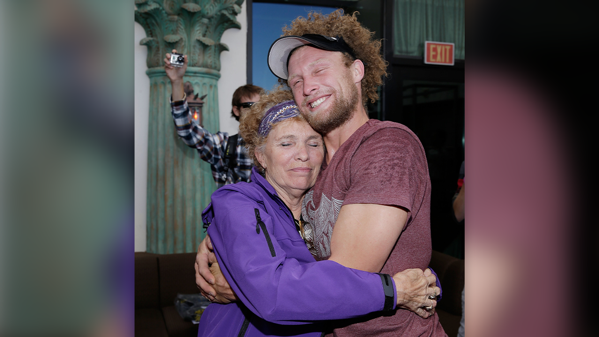 Daredevil Andy Lewis is wearing a achromatic  visor and maroon T-shirt arsenic  helium  has curly, airy  brownish  hairsbreadth  and a abbreviated  beard successful  this photo, wherever  helium  hugs his parent  Lynn aft  mounting  a satellite   grounds   successful  Las Vegas